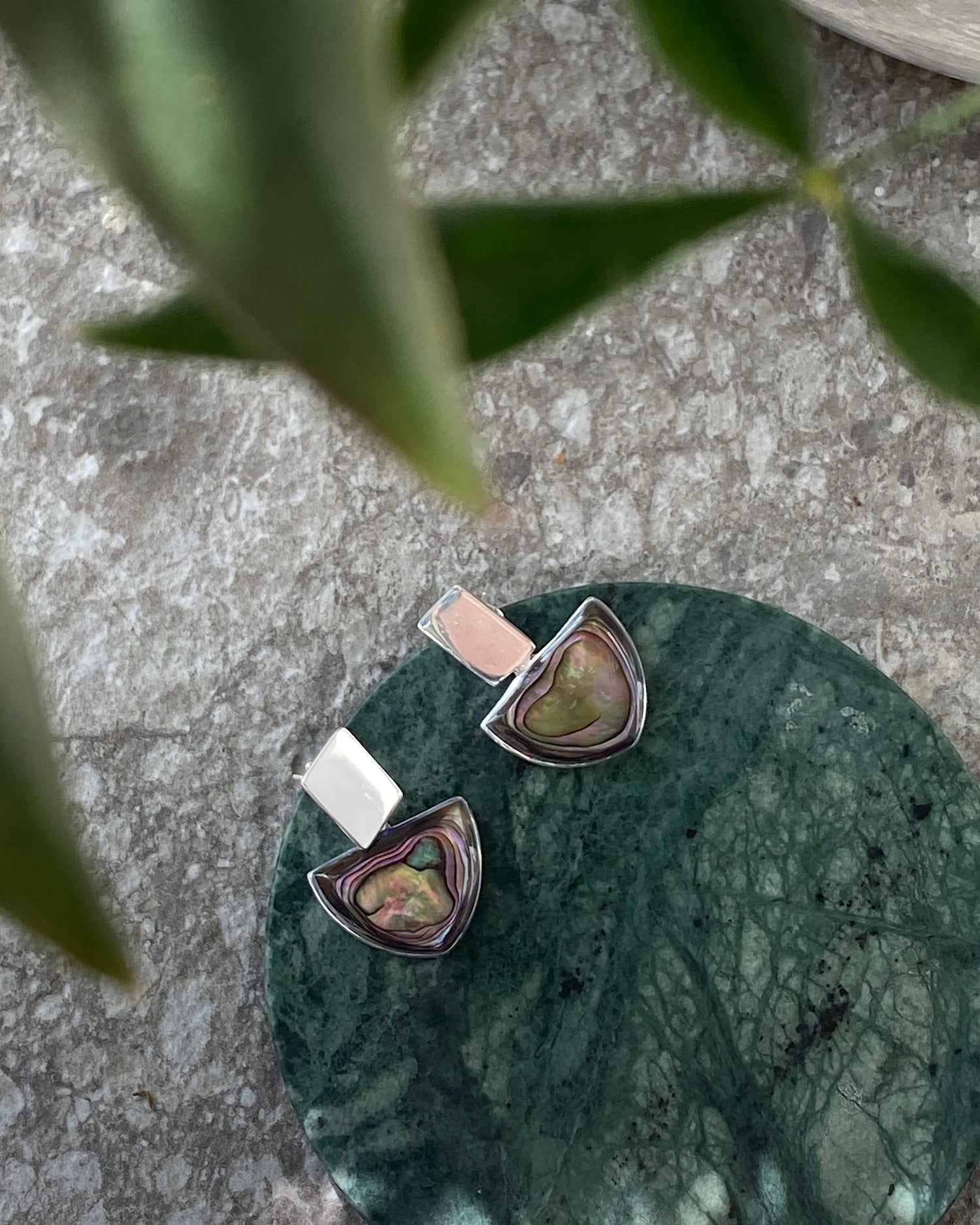 Silver and abalone earrings sit of a green marble circle on a concrete background available at The Pared Store, Surry Hills