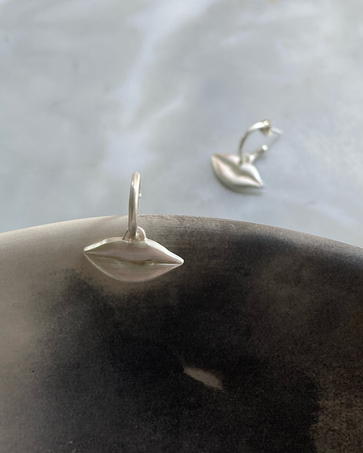 Silver lips charms on a huggie earring