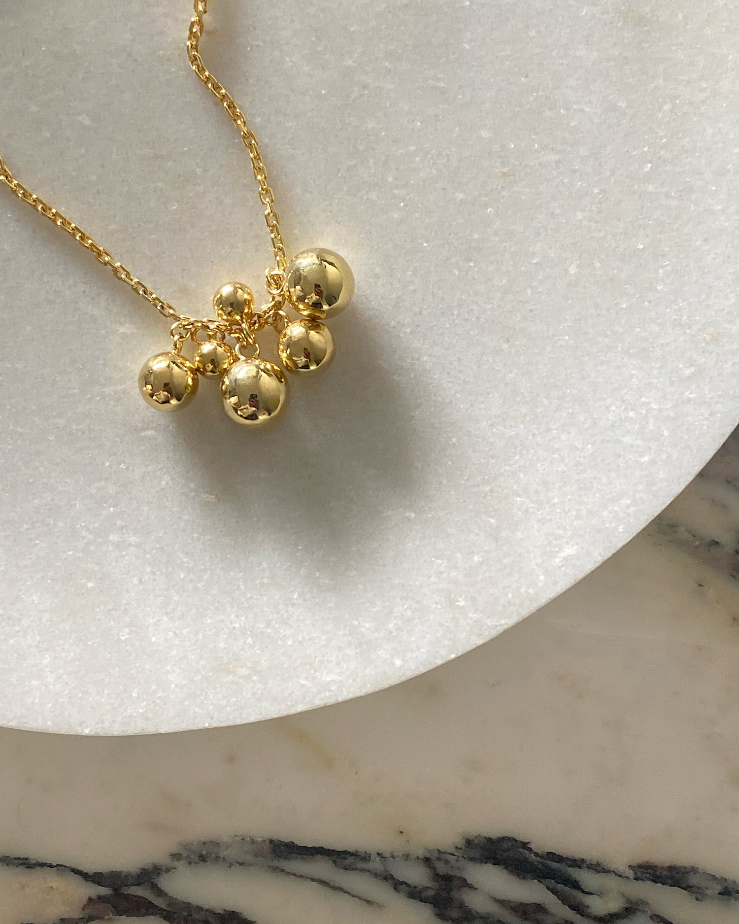 Gold bubbles floating on a gold chain sit on a marble plate