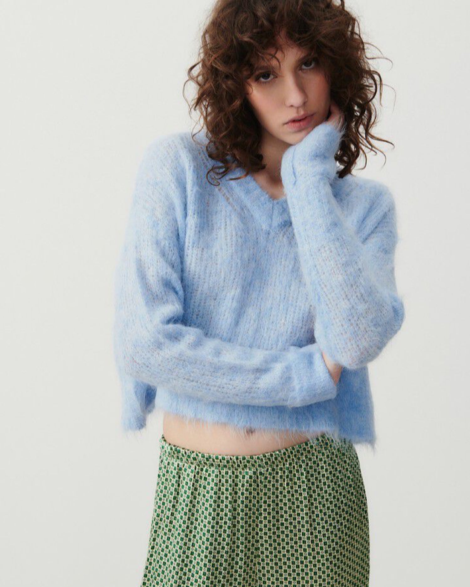 model wears a light bluffy V neck jumper from American vintage with patterned green pants