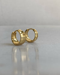 A pair of gold-plated sterling silver hinged huggie hoop earrings with a facetted texture, displayed on a white surface.