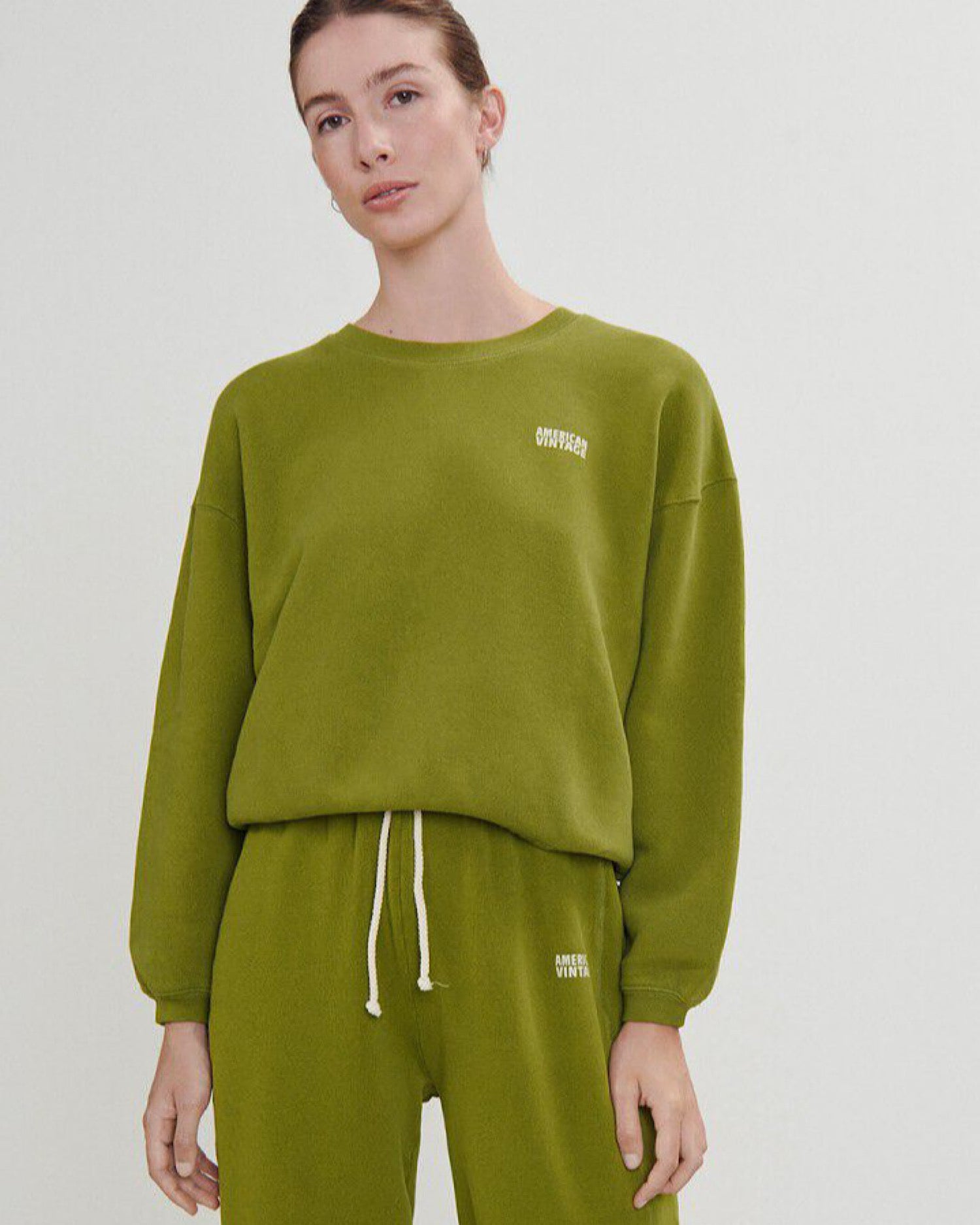 a pea green cropped fleece round neck sweater with a white logo on a modeal