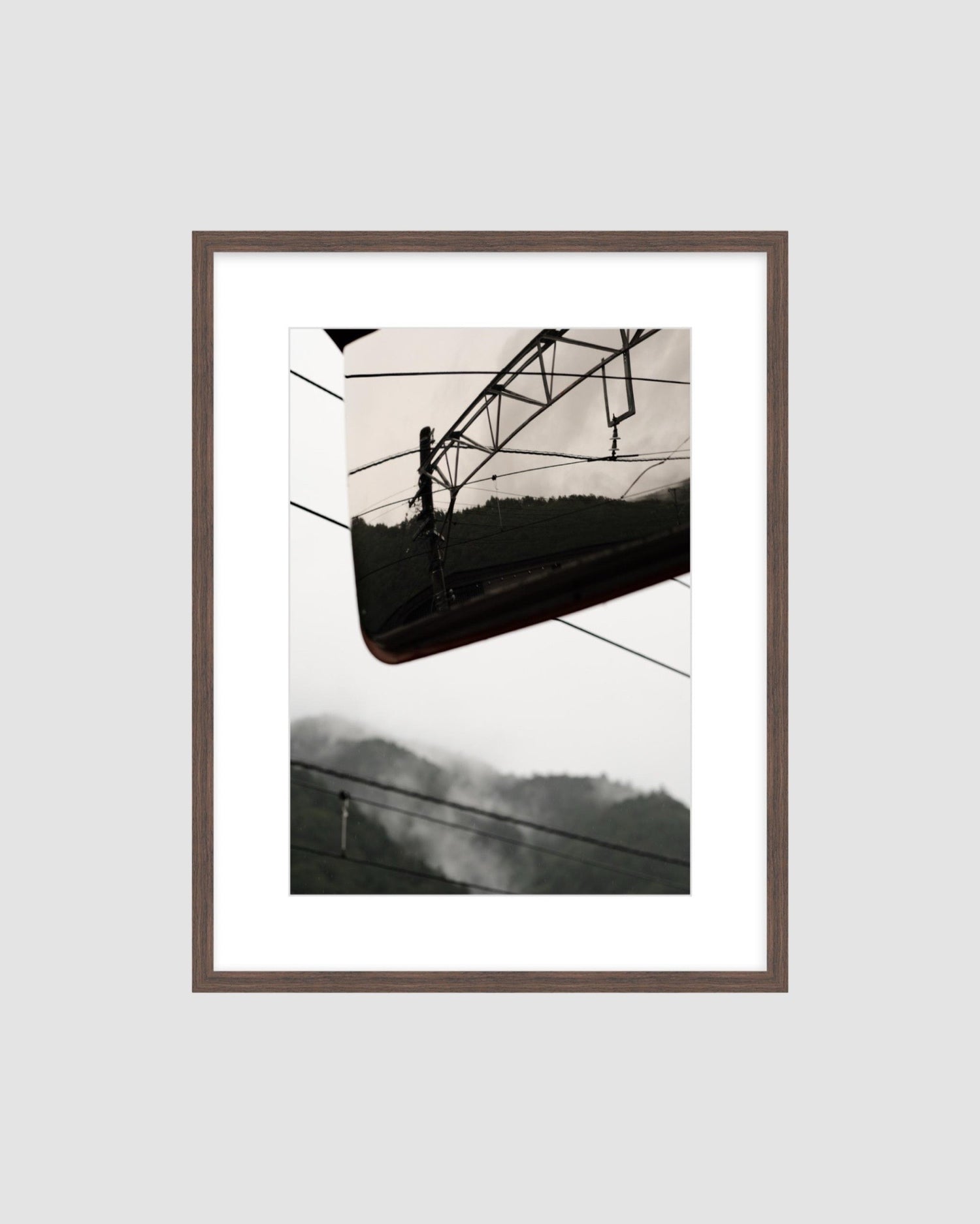 Framed  photograph of a power line and mountains against a light gray background
