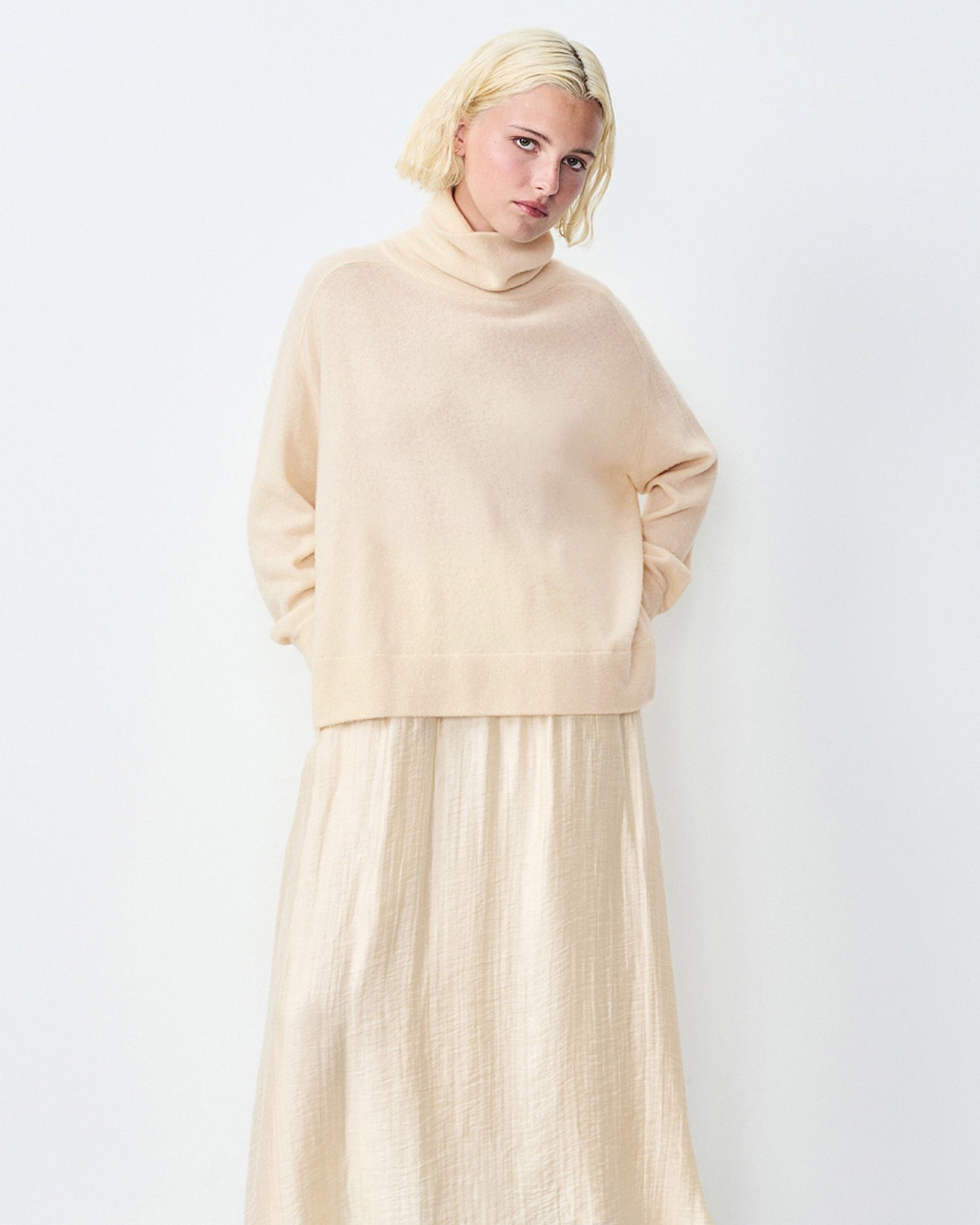 Model wears a cream Raxow Turtleneck sweater from American Vintage