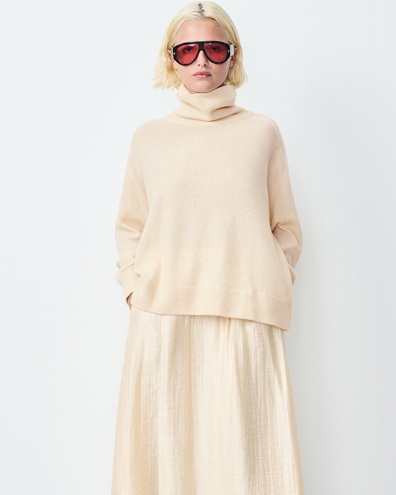 Model wears a cream Raxow Turtleneck sweater from American Vintage