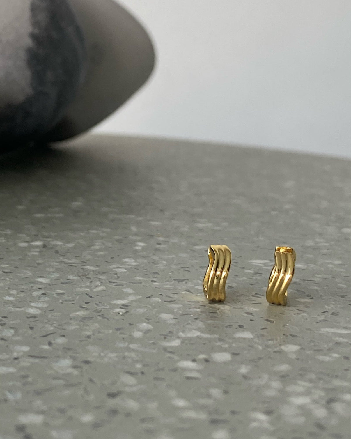 A gold pair a wave shaped small hoops