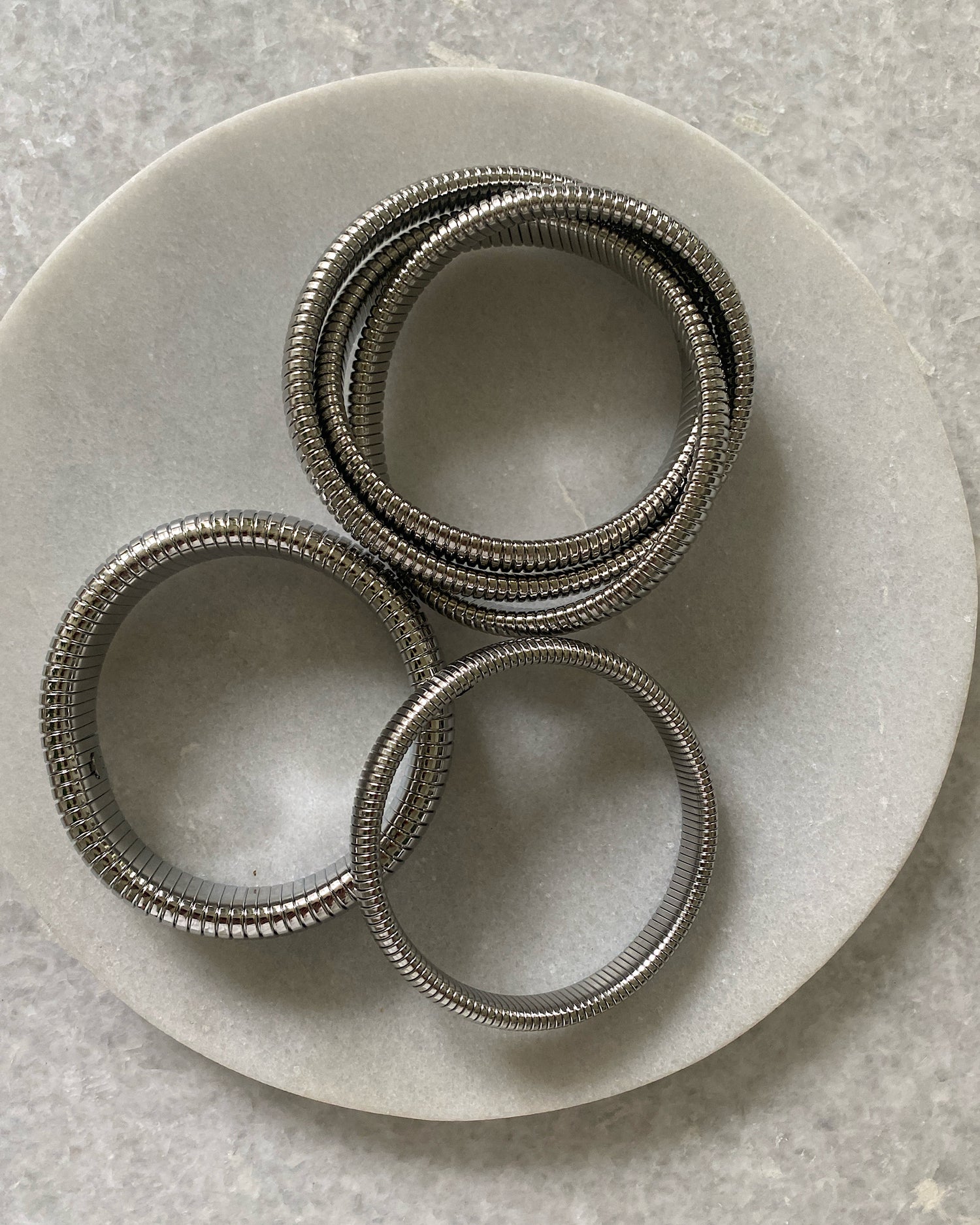 three differing silver snake bangles
