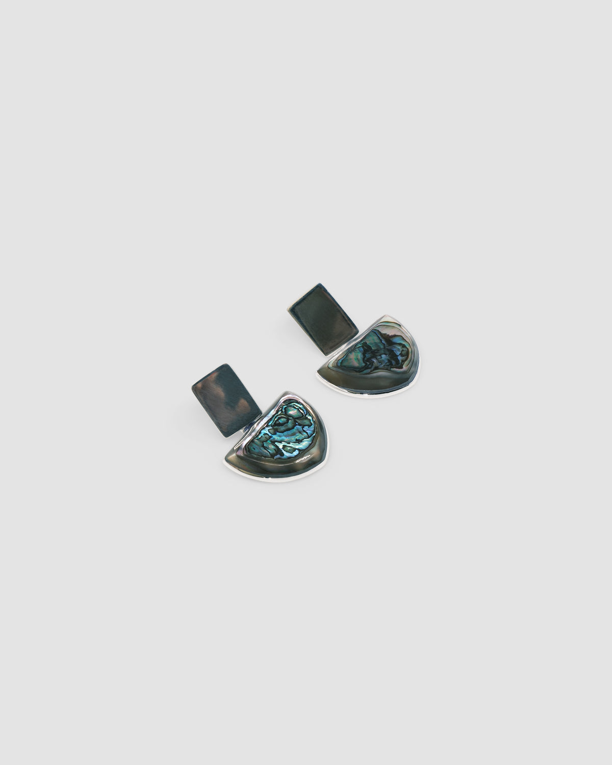 silver rectangle and abalone half circle earrings against a grey background by Carnation Crew