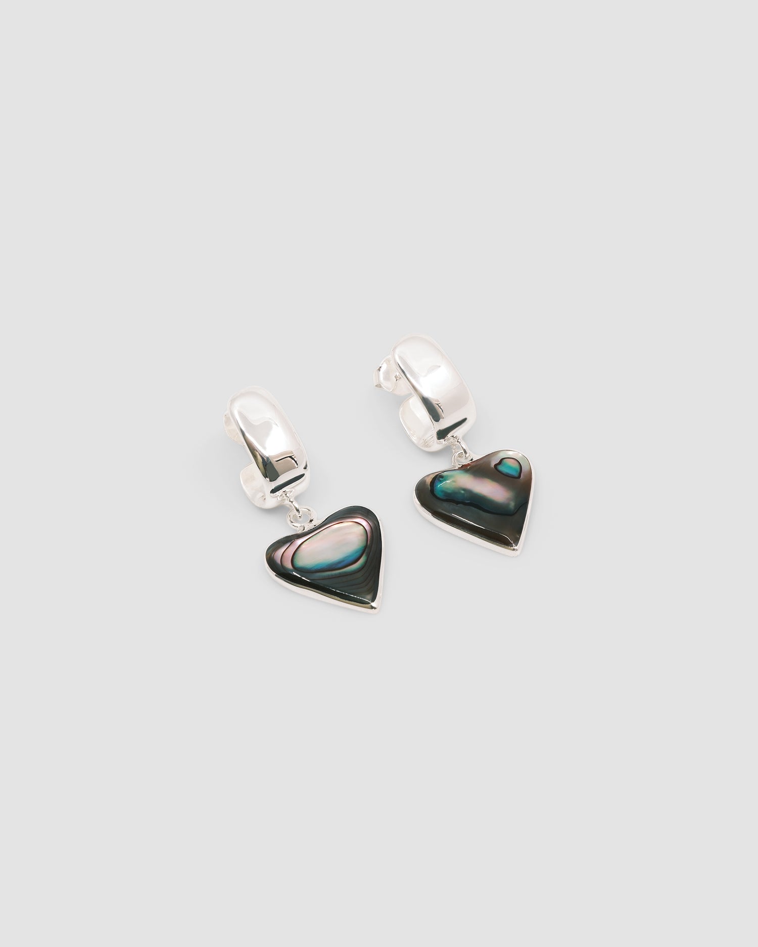 abalone heart charms hang off a silver chubby hoop on a grey background