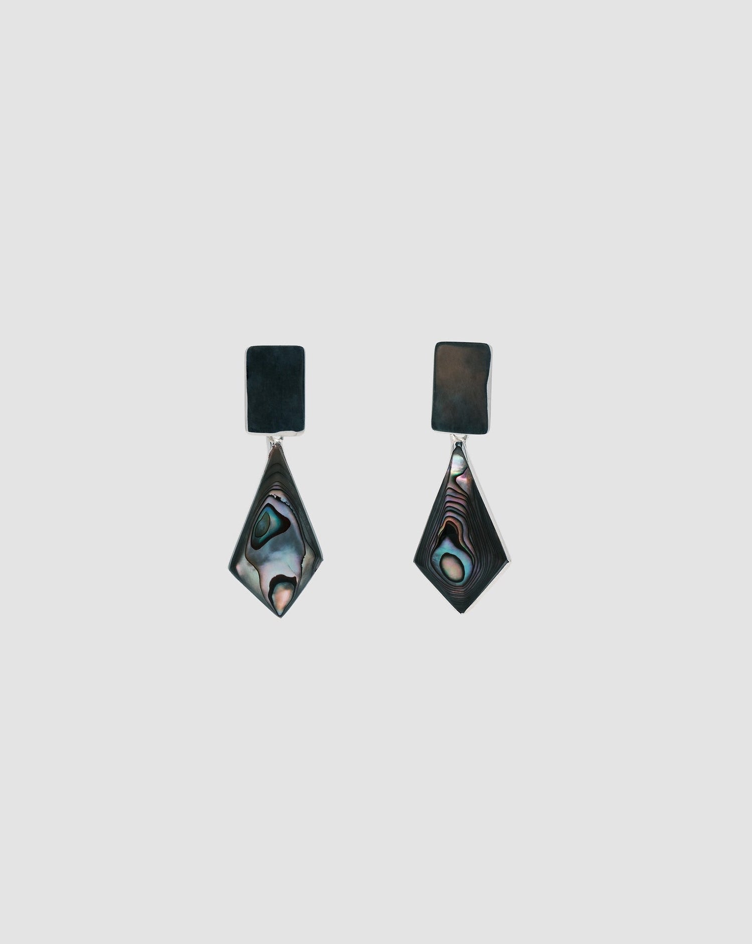 Earrings on a grey background that feature silver rectangle studs with abalone kite shaped charms available in Australia