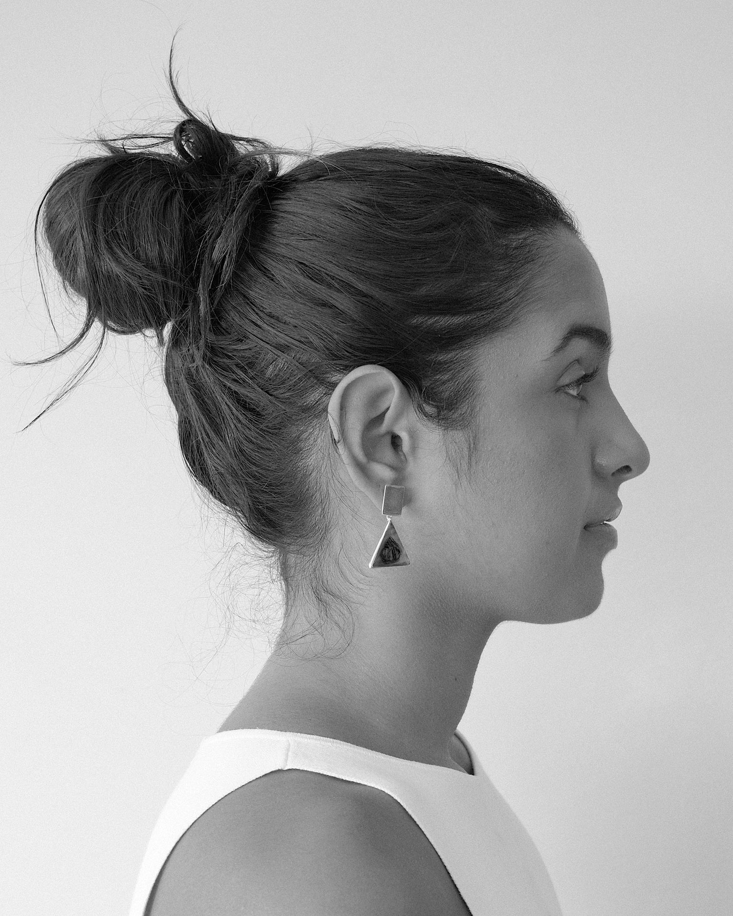 a model wears drop earrings featuring rectangle silver studs with ab alone triangle drops