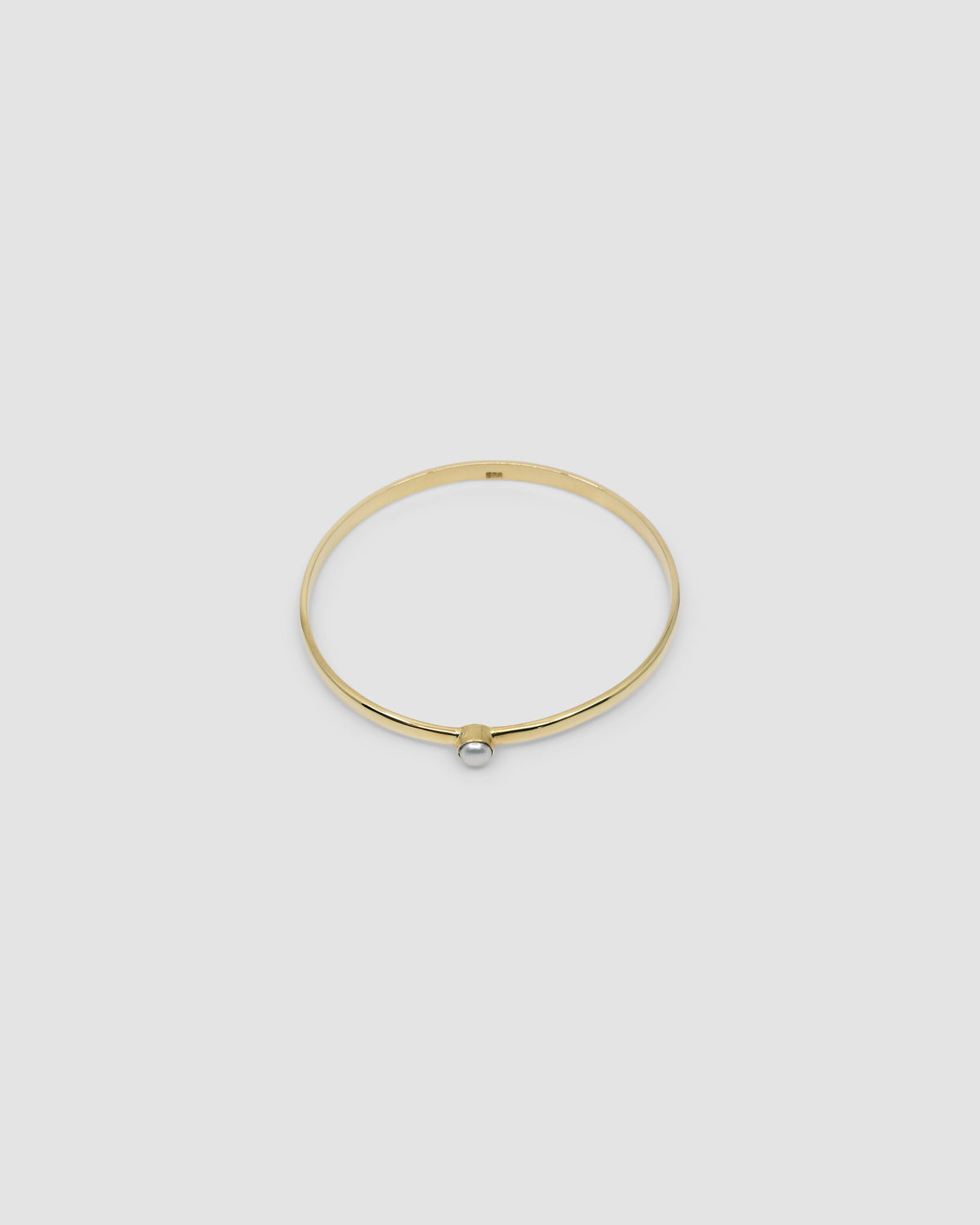 simple thin gold bangle with a single pearl inlaid half way around it