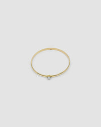 simple thin gold bangle with a single pearl inlaid half way around it