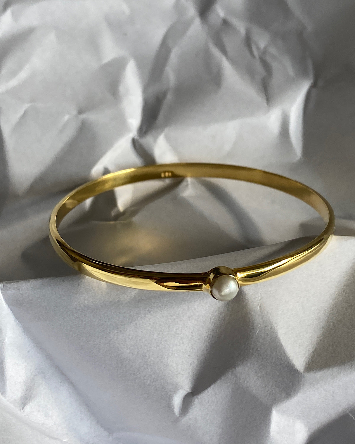simple thin gold bangle with a single pearl inlaid half way around it