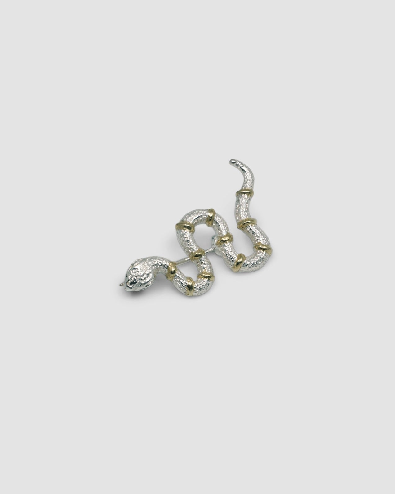 a silver snake brooch with gold stripes