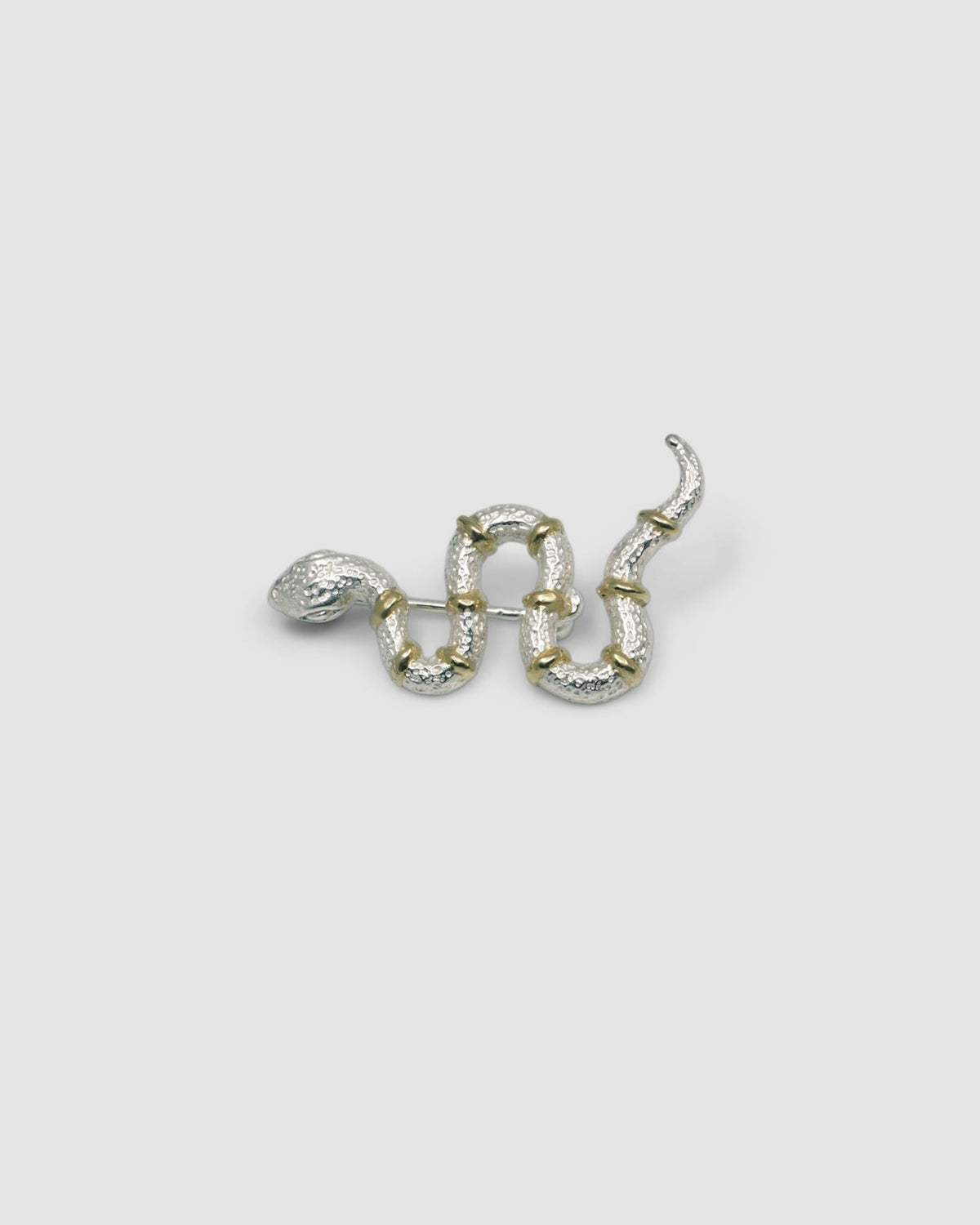 a silver snake brooch with gold stripes