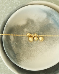 Gold balls on a chain sit ion a bowl from the Pared Store, Foster St