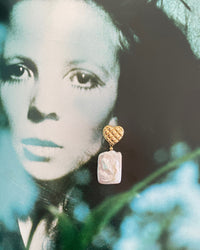 gold quilted studs with rectangular pearls hanging from them sit on a magazine page of a model
