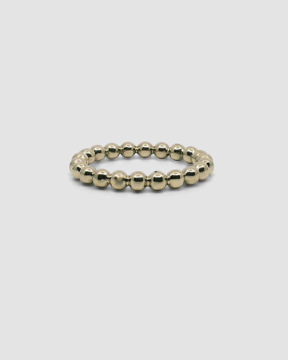 side view of a gold bubble bangle on grey background
