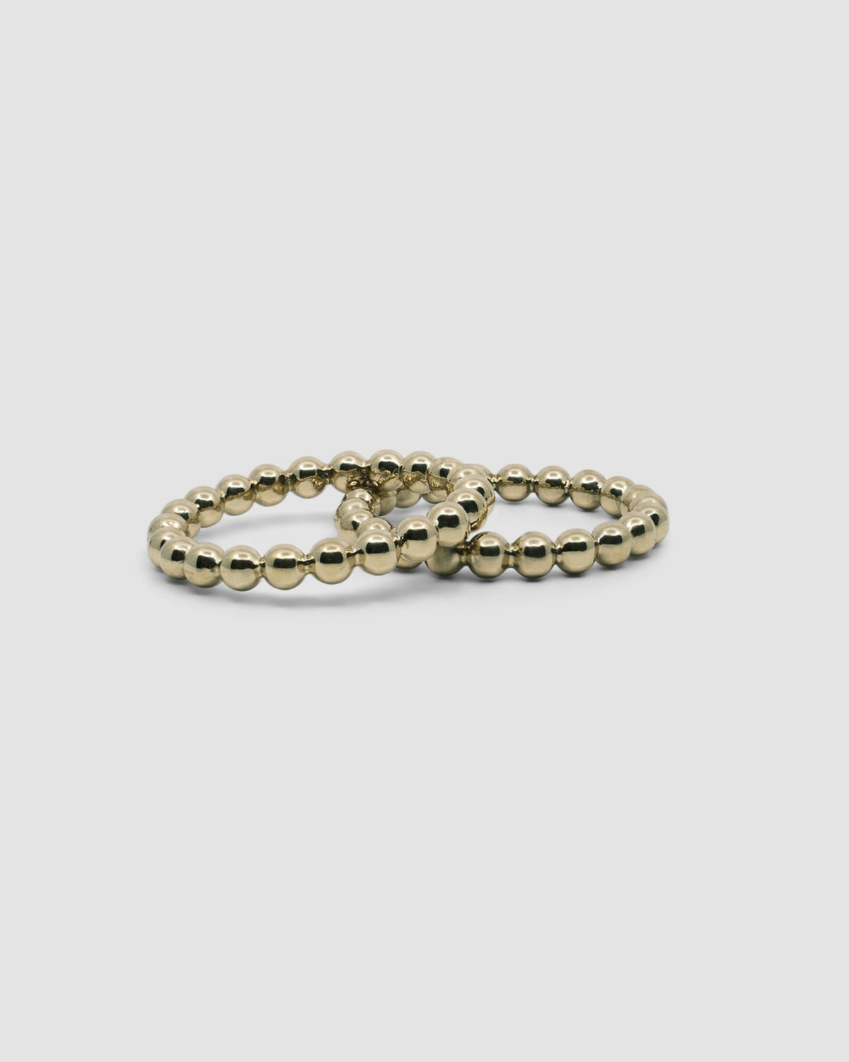 Two brass ball bangles rest on each other