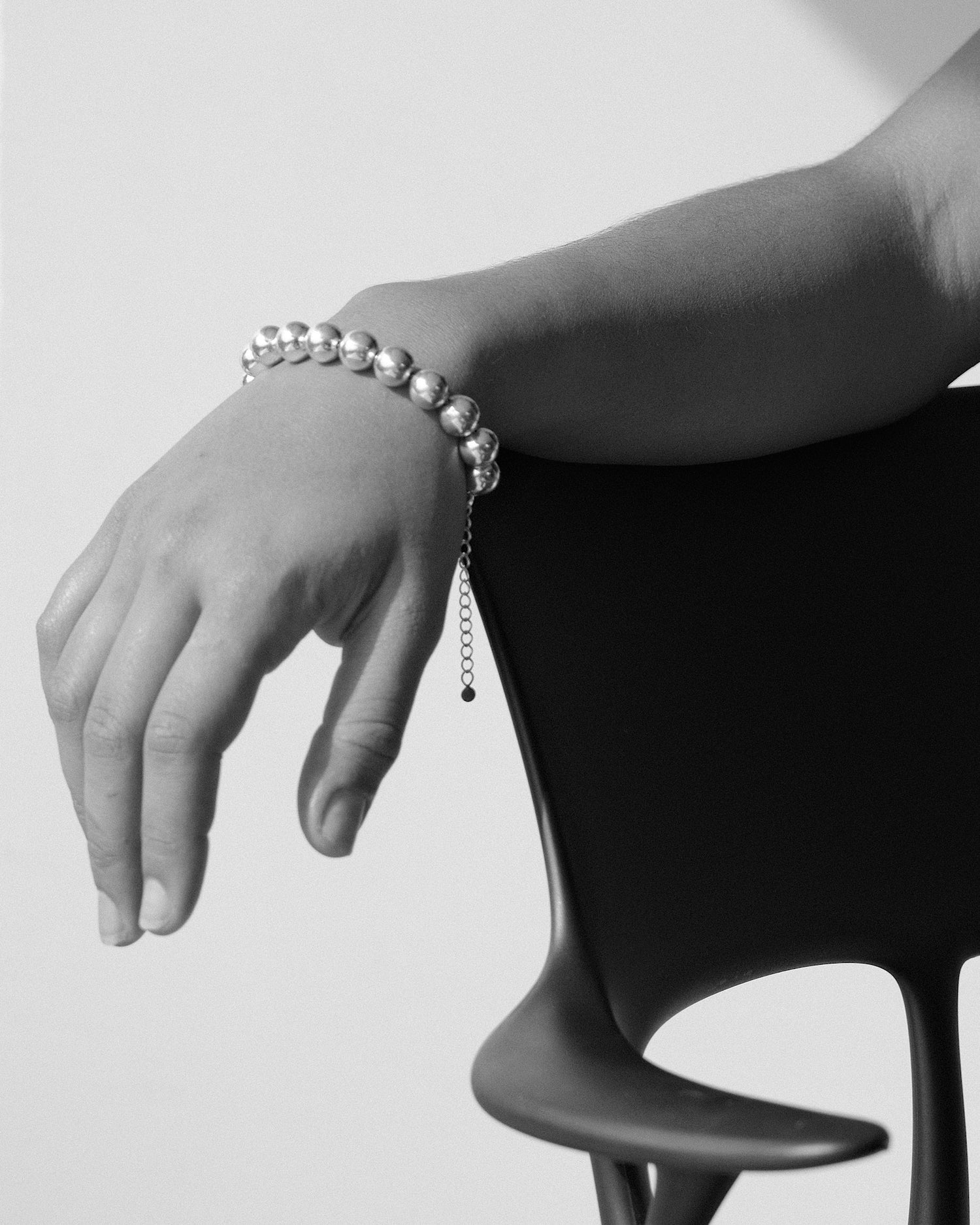 a hand with a bubble style bracelet rests on a chair