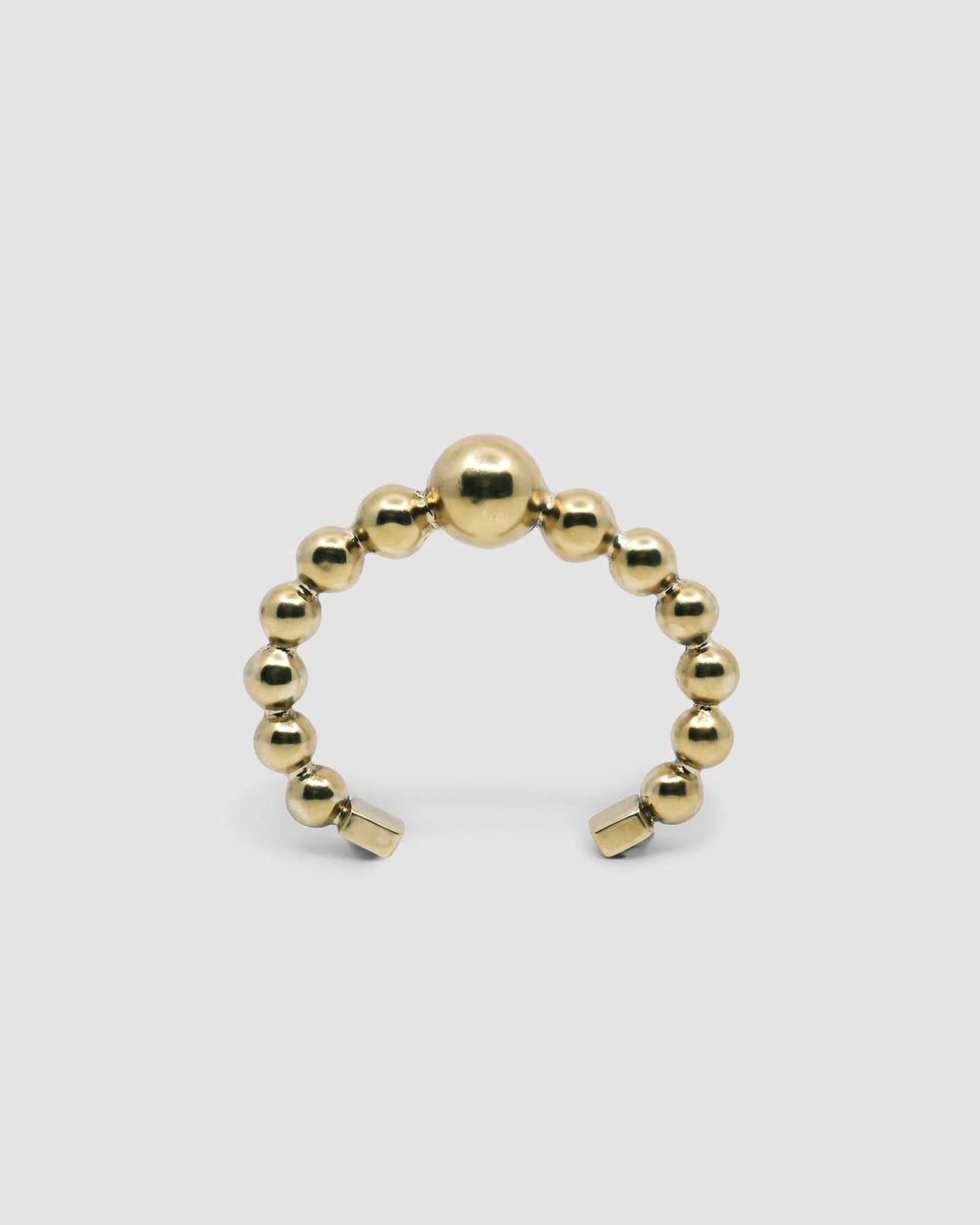 an open gold cuff bangle consisting of numerous interlinked gold balls