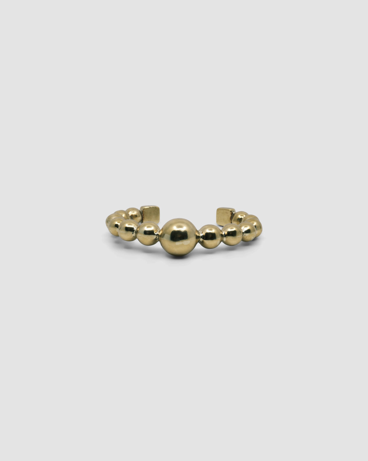 an open gold cuff bangle consisting of numerous interlinked gold balls