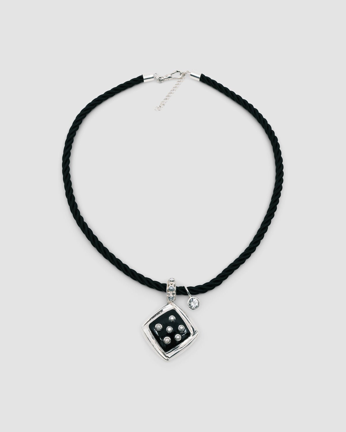Inlaid black pendant studded with pearls sits on a black cord chain