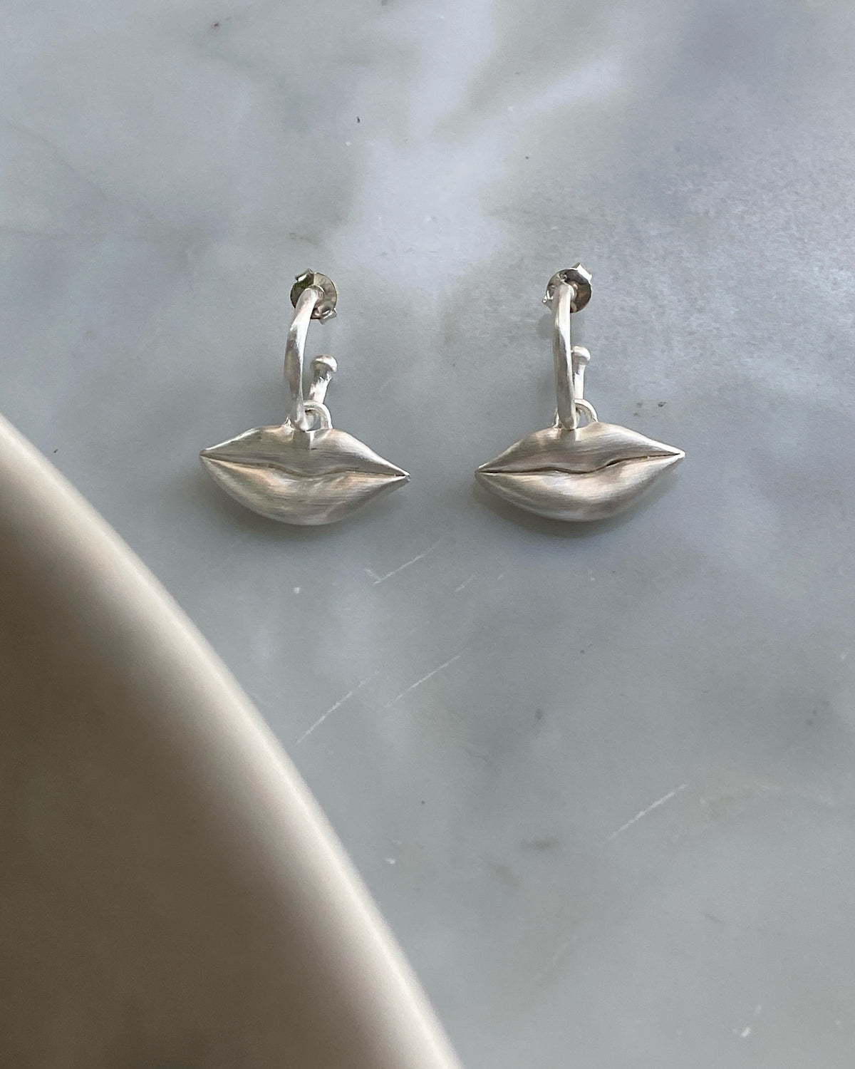 Silver lips charms on a huggie earring