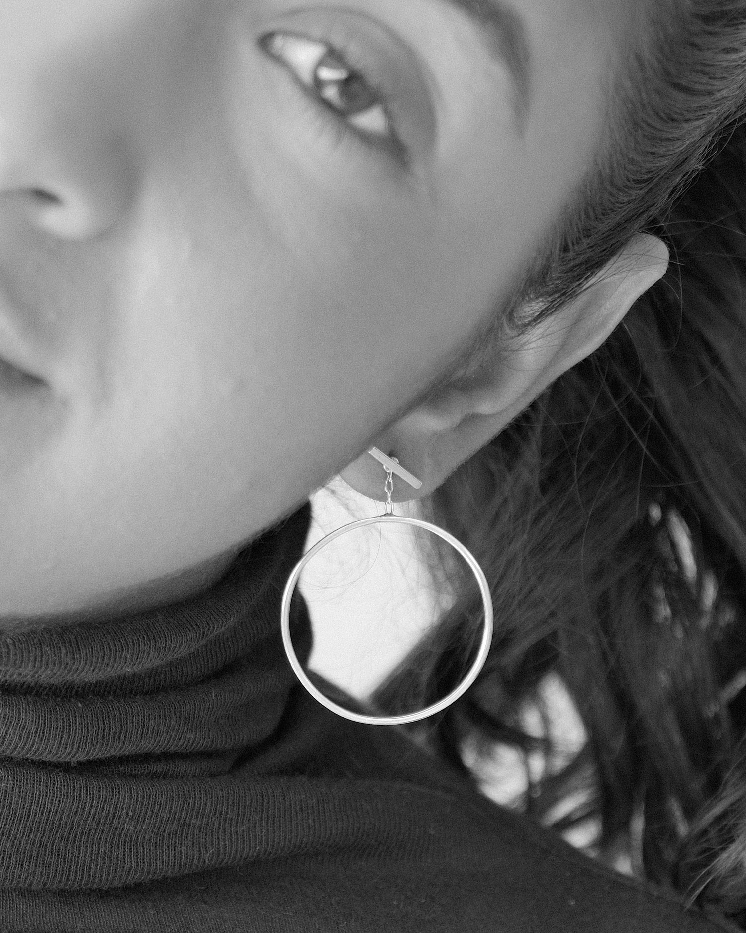 a model wears large drop circle earrings