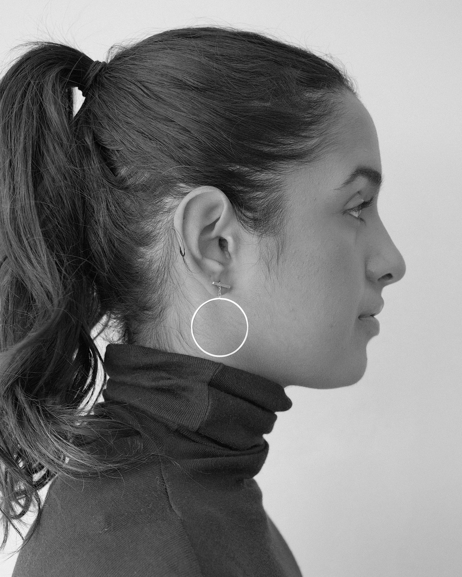 model wears gold circles dangling off a bar