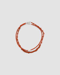 a single baroque pearl floats on a red bead necklace