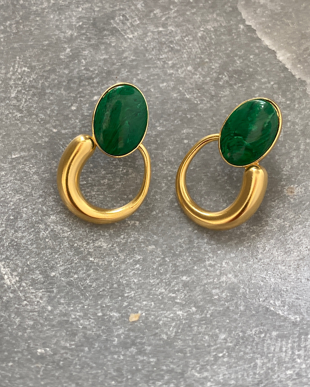 Green stone studs earrings with gold irregular hoops hanging off the bottom in a stone  bowl