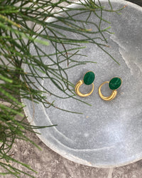 Green stone studs earrings with gold irregular hoops hanging off the bottom in a stone bowl