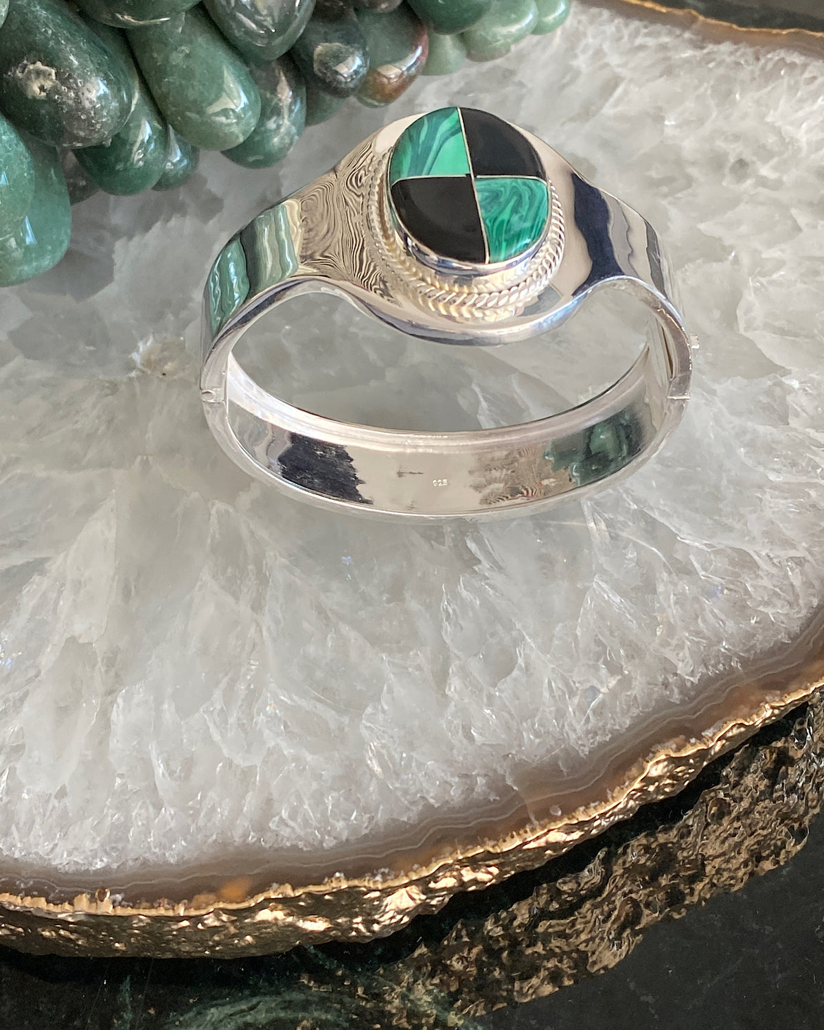 silver cuff bracelet with an inlaid black and green stone