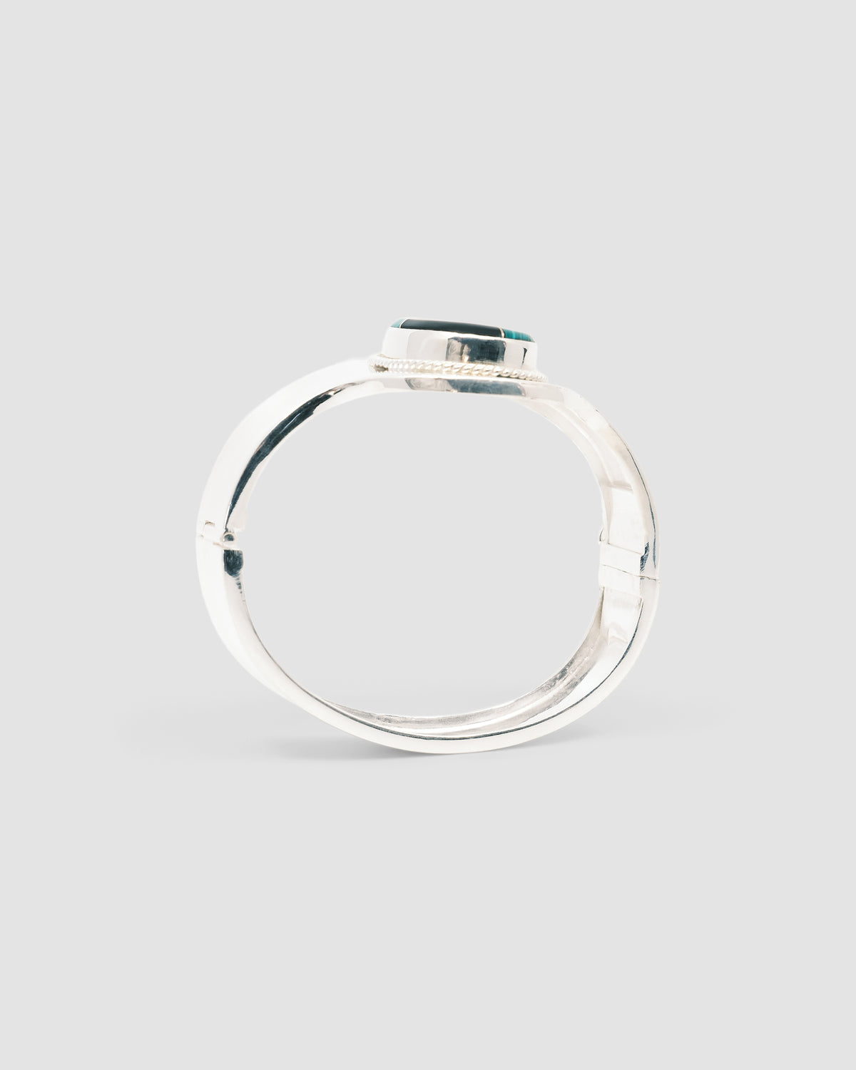silver cuff bracelet with an inlaid black and green stone