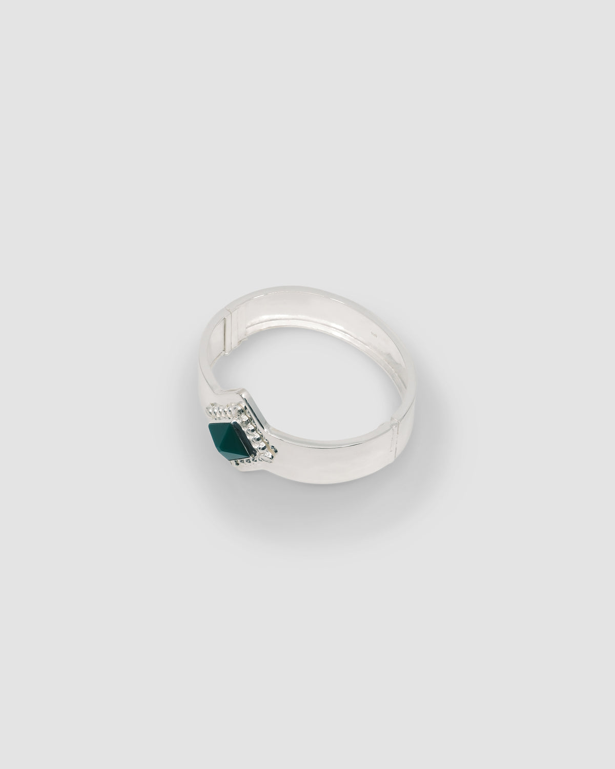 a silver cuff bracelet with a green sqaure stone set into it and beading around the exterior