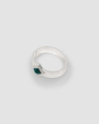 a silver cuff bracelet with a green sqaure stone set into it and beading around the exterior