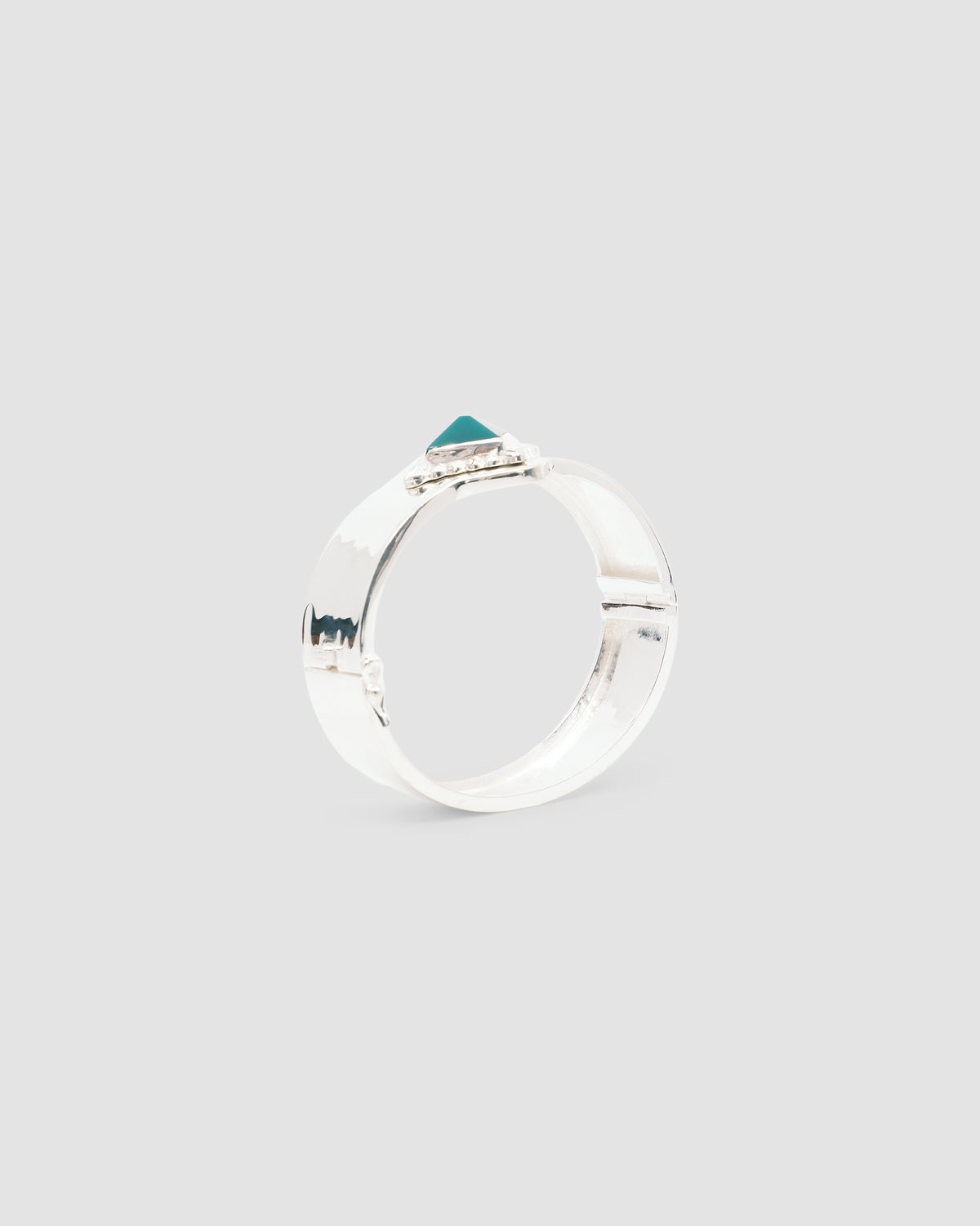a silver cuff bracelet with a green sqaure stone set into it and beading around the exterior
