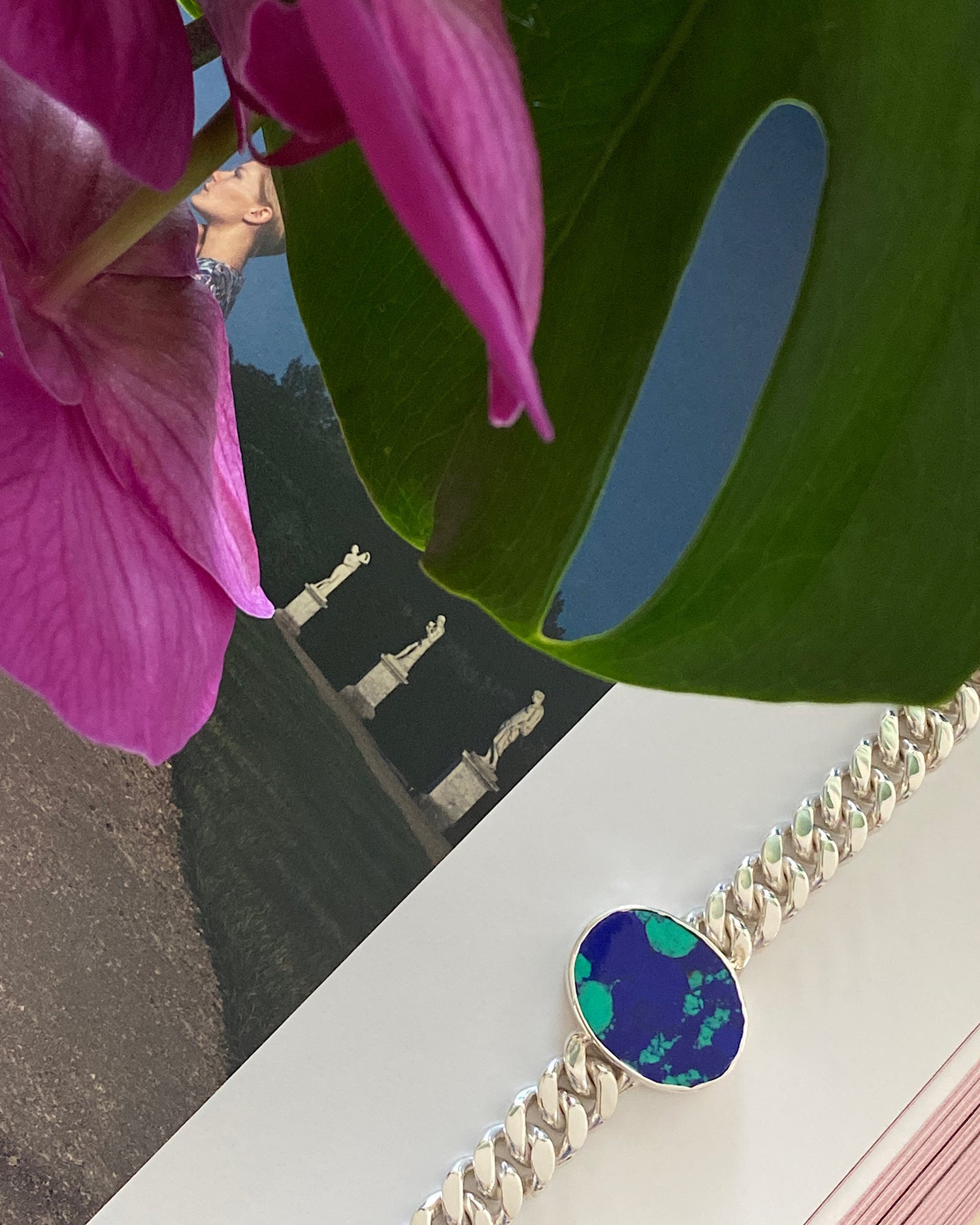 a silver link chain bracalet with a large blue green stone set in the middle