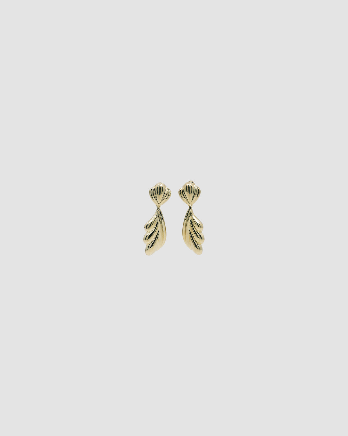 Gold sculptural drop earrings against a grey background