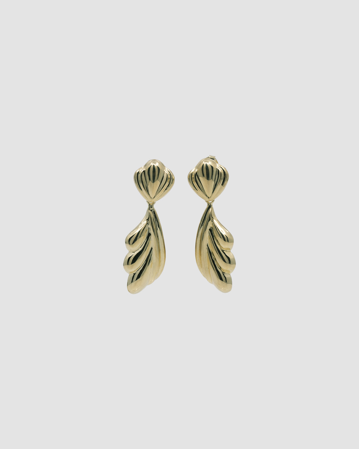 Gold sculptural drop earrings against a grey background