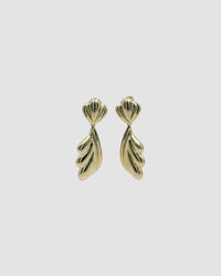Gold sculptural drop earrings against a grey background