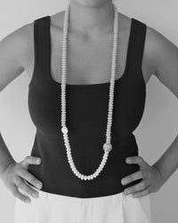 model wears a long beaded necklace with a pearl and feature large handmade bead