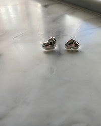 silver heart earrings rest on marble