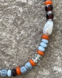 Earth toned assorted beaded glass and pearl necklace on cement