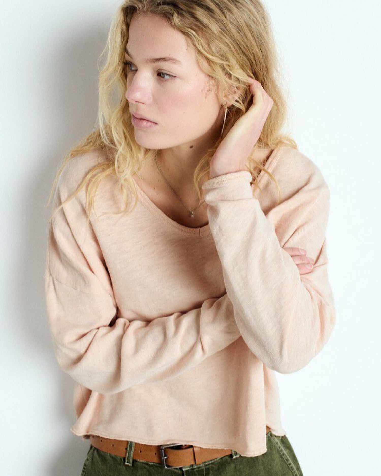 Woman wearing a beige sweater against a plain background