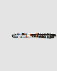Earth toned assorted beaded glass and pearl necklace on a grey background