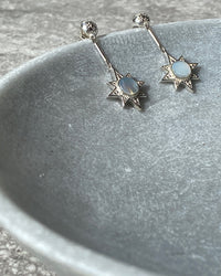 silver star drop earrings sit in a stone bowl