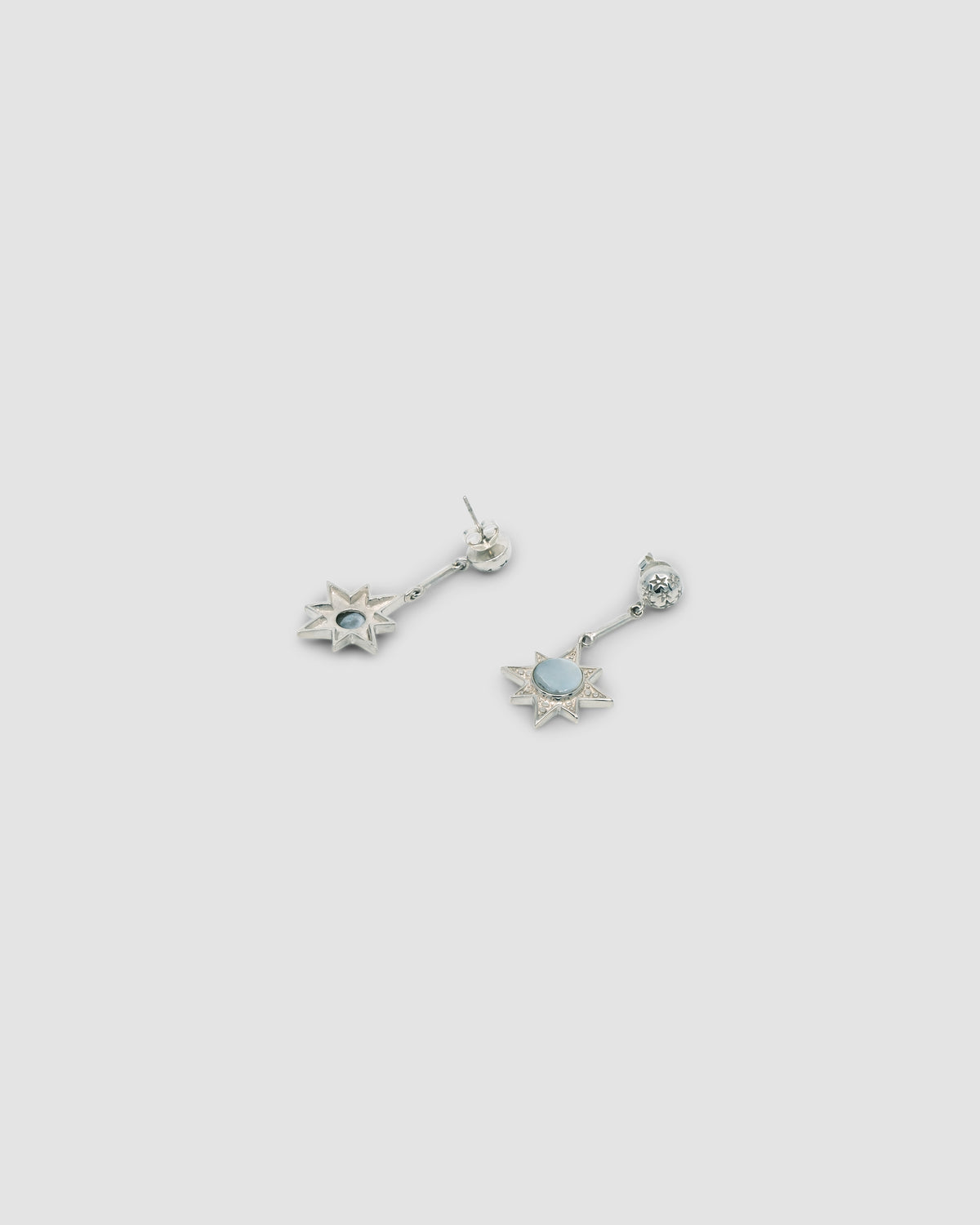 silver star drop earrings pictured front and back sit on a grey background